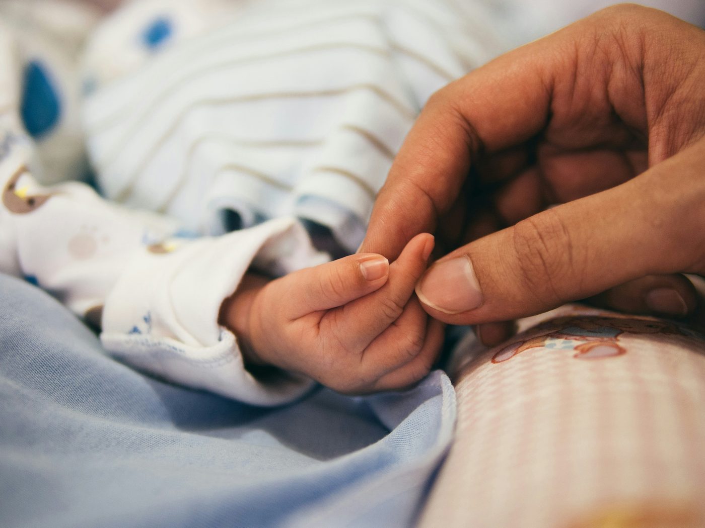 Mother gently holding her baby's hand — a quiet moment of postpartum connection