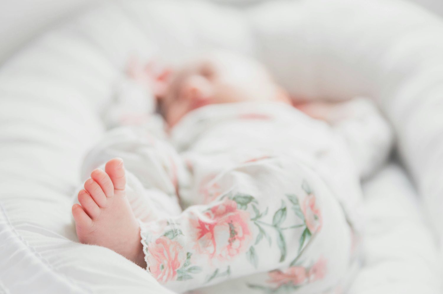 A newborn sleeping peacefully in a soft floral outfit